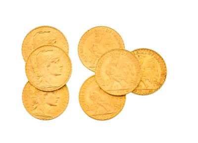 plusieurs pièces d'or sur une surface blanche, avec une pièce d'or au premier plan