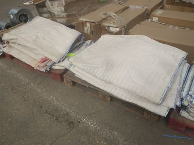 une pile de serviettes pliées posée sur une palette dans un entrepôt