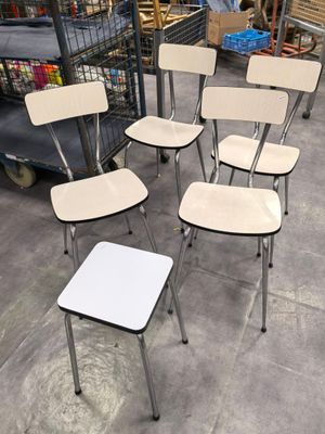 several chairs and a table in a warehouse with a cart in the background