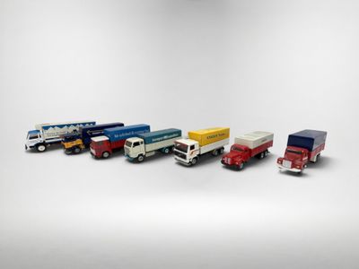 plusieurs camions jouets sont alignés sur une surface blanche