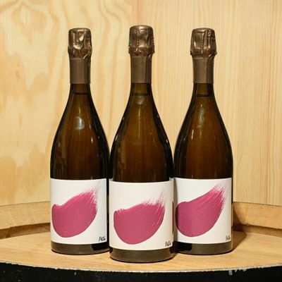 three bottles of wine sitting on top of a wooden barrel