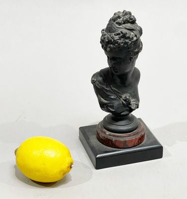 a small statue of a boy with a lemon next to it