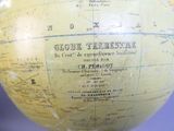 un globe terrestre jaune, sur lequel figure une carte, posé sur une table