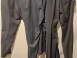 two men ' s pants hanging on a clothes rack in a room