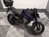 une moto violette et noire garée sur un sol à damier dans un garage
