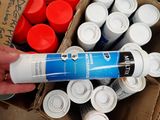 a person holding a tube of paint in front of a box of cans