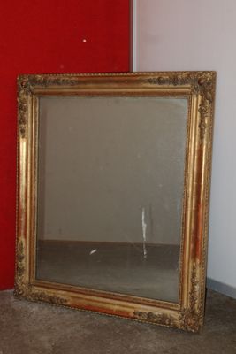 a mirror that is sitting on the floor next to a red wall