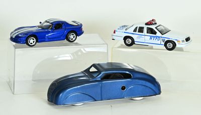 trois petites voitures exposées sur une étagère transparente
