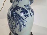a blue and white vase on a table with a lamp on it