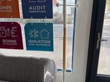 a couch and a lamp in front of a window with signs on it