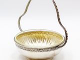 an antique silver plated bowl with a handle on a white background