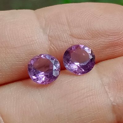 deux saphirs violets au doigt d'une personne, dans une main