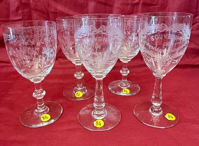 six verres à vin vides sont alignés sur une nappe rouge