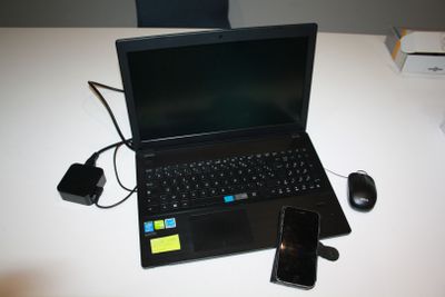 un ordinateur portable posé sur une table, à côté d'un téléphone portable et d'une souris