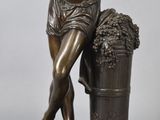 a bronze statue of a man sitting on a barrel with grapes