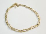 gros plan d'un bracelet en chaîne en or sur une surface blanche