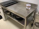 un ordinateur portable posé sur une table de cuisine, sur laquelle se trouvent des casseroles et des poêles