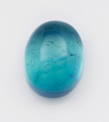 œuf en verre bleu posé sur une surface blanche, sur fond blanc