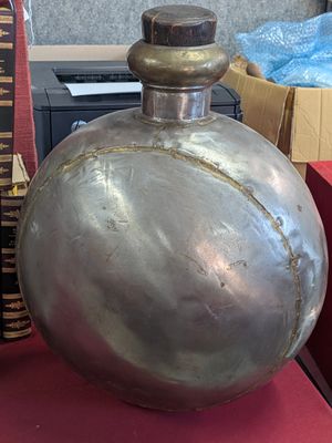 a large metal flask sitting on a table next to a stack of books