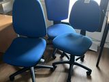 trois chaises de bureau bleues posées sur un parquet en bois massif