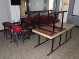 des tables et des tabourets dans une pièce où un miroir est accroché au mur