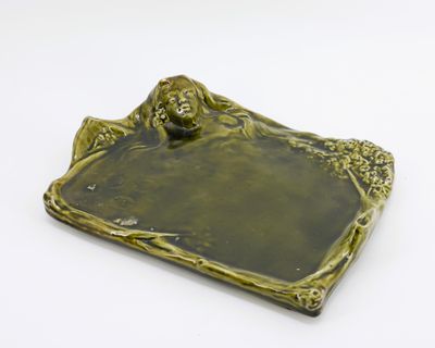 Dessous de plat en faience verte a décor figurant une femme.…