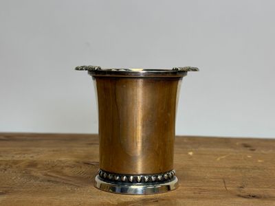 silver plated cup on wooden table with white wall in background