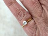 la main d'une personne tenant une bague en or sertie d'un diamant