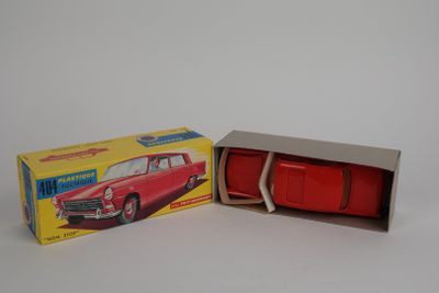 une petite voiture rouge dans une boîte sur une surface blanche