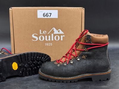 pair of black boots with red laces next to a box of shoes
