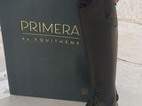black leather riding boots on display in front of a box of primera