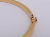 a close up of a gold plated bracelet on a white surface