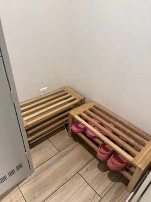 un parquet en bois massif dans une salle de bains aux murs blancs, avec une étagère en bois pour les chaussures