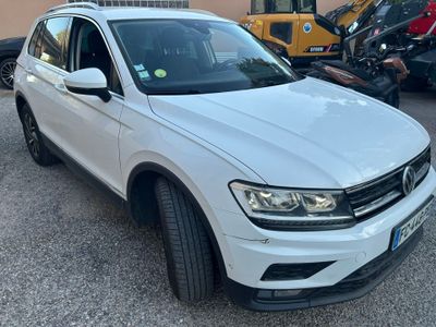 a white volkswagen tigua parked in a parking lot next to other cars