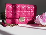 a pink purse sitting on a table next to a pink flower