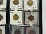 several different coins are in a plastic case on a white surface