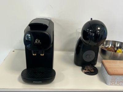 une cafetière noire posée sur un plan de travail, à côté d'un bol argenté