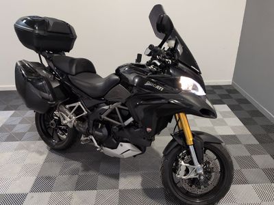 une moto noire garée dans une pièce au sol en damier