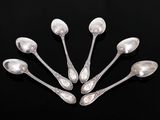six cuillères en argent sont disposées en cercle sur une surface noire