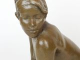 bronze statue of a young girl sitting on a rock