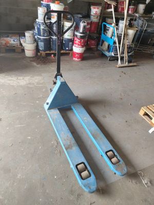 a blue forklift sitting in a garage next to a pallet