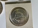 three silver coins sitting next to each other on a white surface
