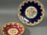 two plates with floral designs on them sitting on a table