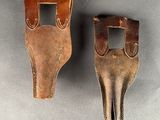 two brown leather holsters with one open and the other closed