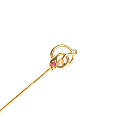 une photo d'une broche en or ornée d'une pierre rose