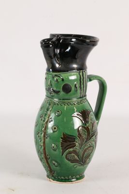 un vase vert avec une anse noire sur fond blanc