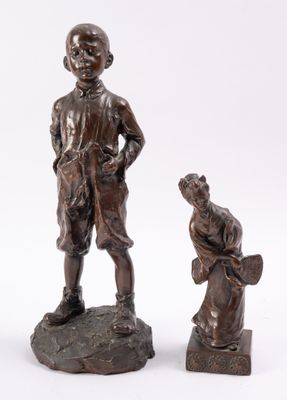 deux figurines en bronze représentant un garçon et un chien assis sur un rocher