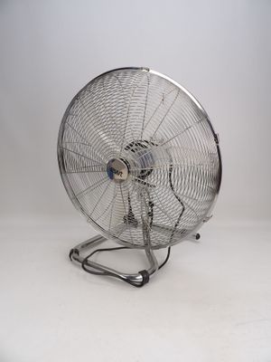 un ventilateur métallique posé sur une surface blanche