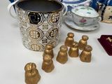 several gold figurines are sitting on a table next to a cup of coffee