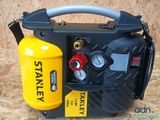 a close up of a compressor on a wooden surface with a yellow canister